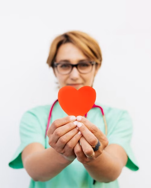 doctora con un un baumanómetro y un corazón de papel en color rojo en la mano
